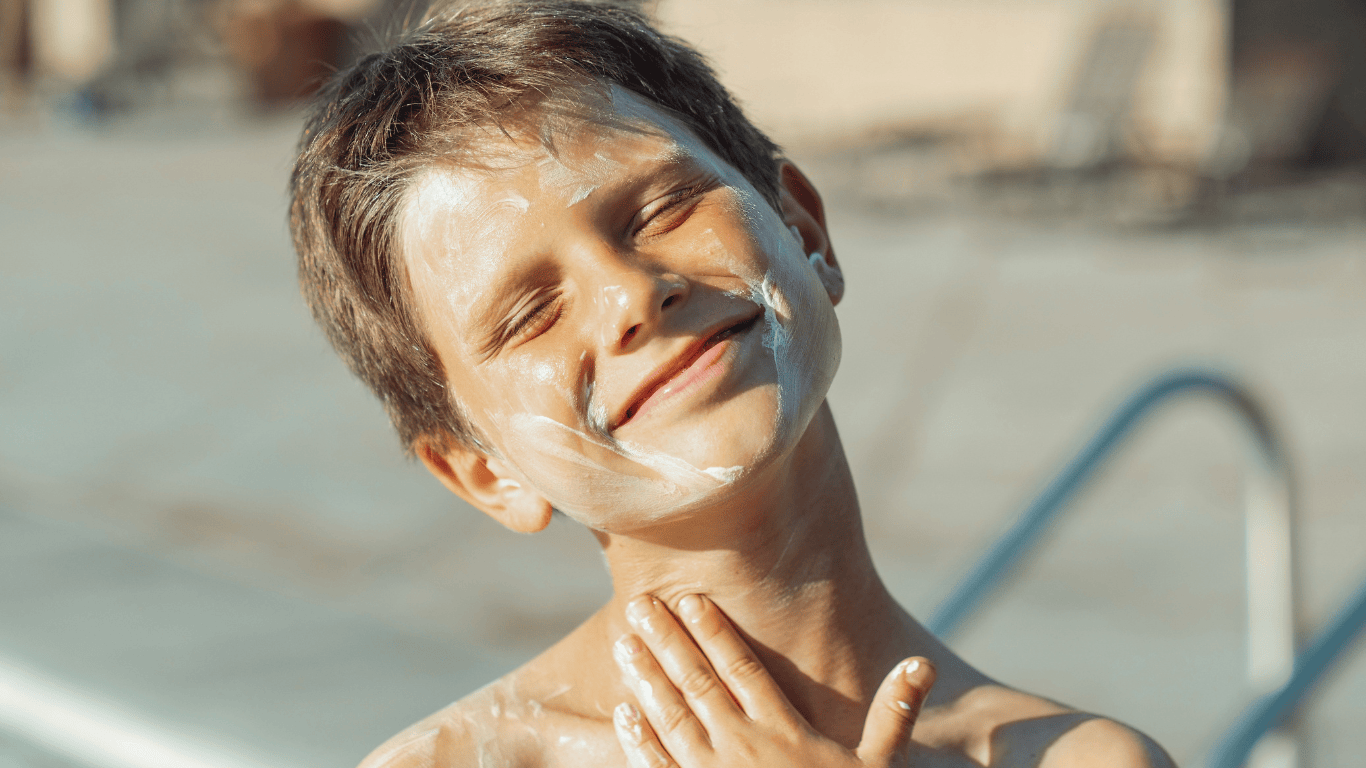 Primer plano de un niño al sol con crema solar por toda la cara